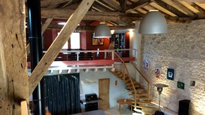 Un interior rústico con vigas de madera a la vista, una escalera, un comedor y una cocina.