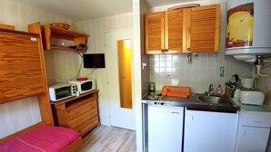 Une cuisine compacte avec des meubles en bois, un four à micro-ondes, un petit réfrigérateur et un évier.
