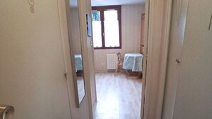 Un couloir étroit mène à une pièce dotée d’une fenêtre et d’une table recouverte d’une nappe.