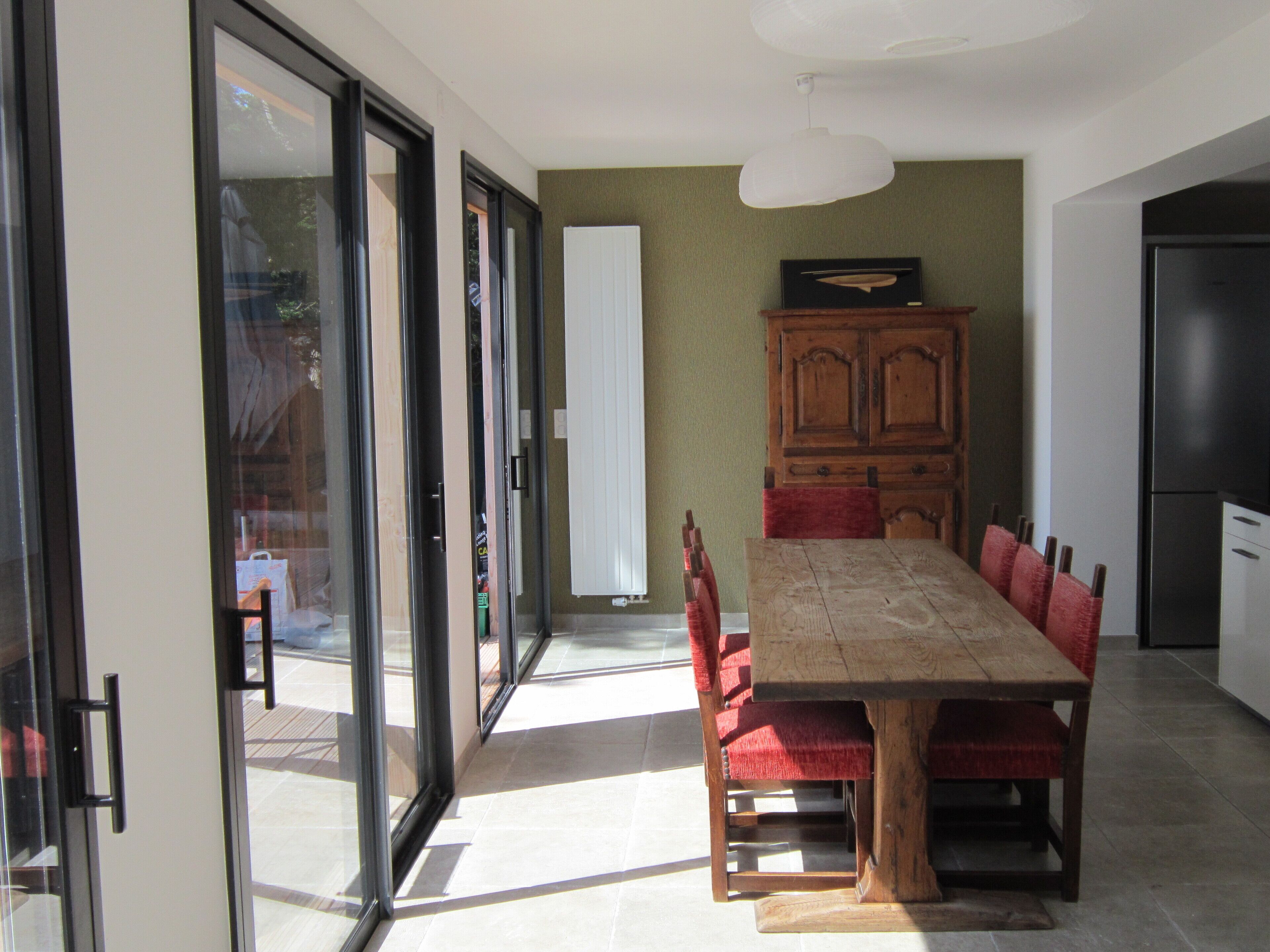 A dining area with a wooden table and red chairs, a cabinet, and a refrigerator.