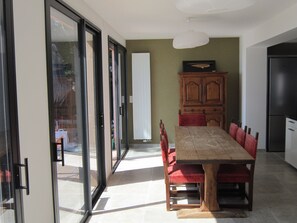 Un coin repas avec une table en bois et des chaises rouges, un buffet et un réfrigérateur.