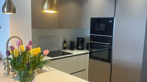Una cucina moderna con isola centrale, illuminazione a sospensione, forno integrato e macchina per il caffè.