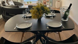 Zona pranzo con tavolo apparecchiato per due, divano e vista sul mare.