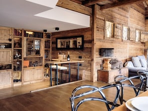 A rustic interior with wooden walls, a dining area with metal chairs, and a bar area. - 5★ chalet, 12 people, spa, sauna, near slopes, 5 rooms (La Clusaz)
