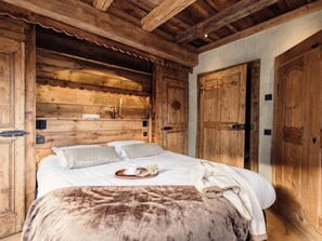 A wooden room with a bed, a wooden wardrobe, and a door. - 5★ chalet, 12 people, spa, sauna, near slopes, 5 rooms (La Clusaz)