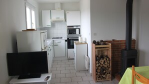 A compact kitchen with white appliances, a TV, and a wood-burning stove. - Furnished tourist accommodation 3 * south ardèche with shared pool (Rosières)