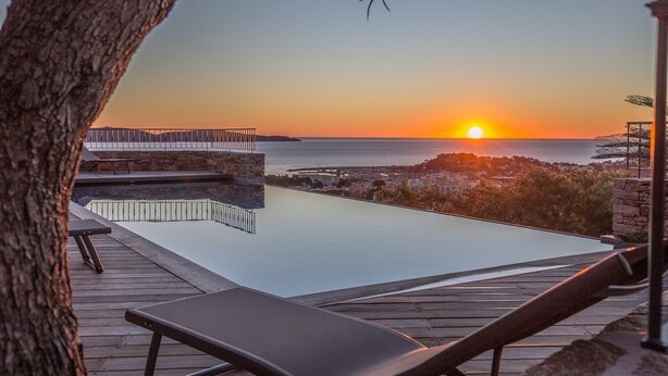 A rooftop infinity pool with a view of the sunset over the sea, wooden deck, and lounge chairs. - VILLA SOLEIL D'OR GOLFE DE ST TROPEZ4*, swimming pool at 29° all year round, 180° view (Cavalaire-sur-Mer)