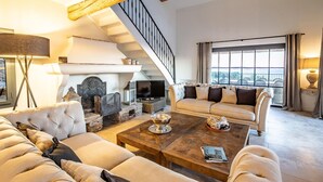A spacious living room with a fireplace, a sofa set, a coffee table, and a staircase. - VILLA SOLEIL D'OR GOLFE DE ST TROPEZ4*, swimming pool at 29° all year round, 180° view (Cavalaire-sur-Mer)