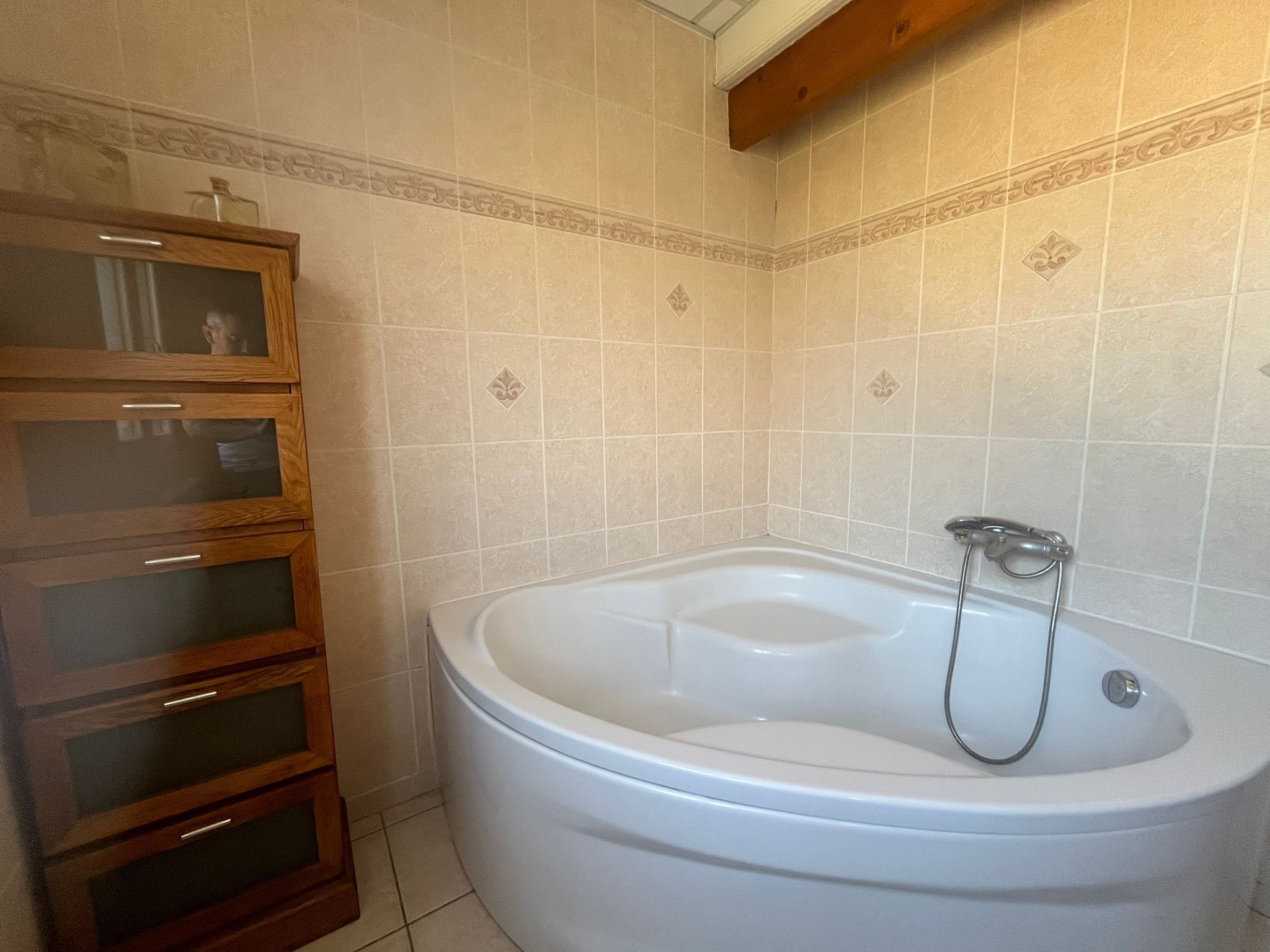 Ein Badezimmer mit freistehender Badewanne, Holzschränken und gefliesten Wänden.
