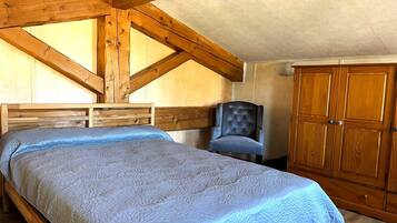 Ein Schlafzimmer mit einem Bett, einem Sessel und einem Holzschrank.