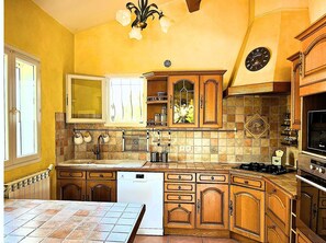 A kitchen with wooden cabinets, a dishwasher, a stove, and a clock on the wall. - Villa with private pool, quiet and not overlooked near Avignon (Althen-Des-Paluds)
