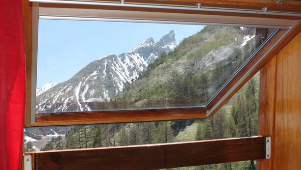 Una habitación con un amplio ventanal que ofrece vistas a una cadena montañosa.