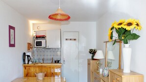 Una cocina compacta con una mesa y banco de madera, un microondas y una lámpara colgante.