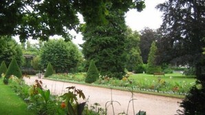 A well-maintained garden with a variety of plants and trees, a gravel path, and a bench in the background. - holidays in GERARDMER 100m from the lake (Gérardmer)