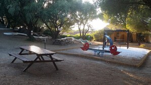 Ein Spielplatz mit Wippe, Schaukel und Picknicktisch.