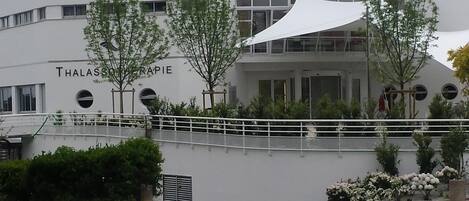 Un edificio moderno con estructura circular, llamado 'Miramar Cruise Hotel Thalasso', que presenta un balcón y un área cubierta con árboles.