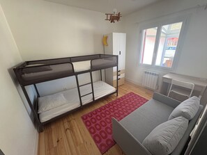 A room with a bunk bed, a desk, a chair, and a window.