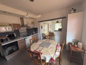 Une cuisine compacte avec un coin repas, comprenant un four à micro-ondes, une cuisinière et une machine à café.