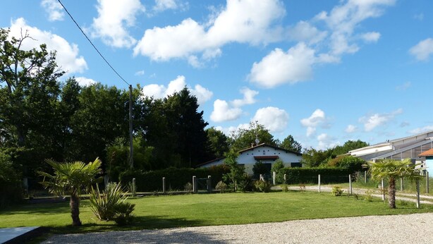 A building with a white exterior and a red roof, surrounded by a gravel driveway and a well-maintained lawn. - PAX HOUSE - at the lake Hourtin - 6 beds (Hourtin)