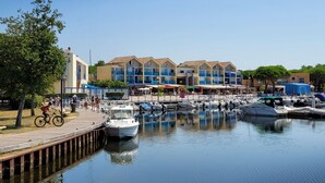 A marina with boats docked, a wooden boardwalk, and buildings with balconies. - PAX HOUSE - at the lake Hourtin - 6 beds (Hourtin)