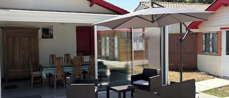 A patio area with wicker furniture, a glass door leading to a room, and a red roof.