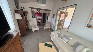 A living room with a sofa, a wooden coffee table, a television, and a wooden cabinet. - PAX HOUSE - at the lake Hourtin - 6 beds (Hourtin)