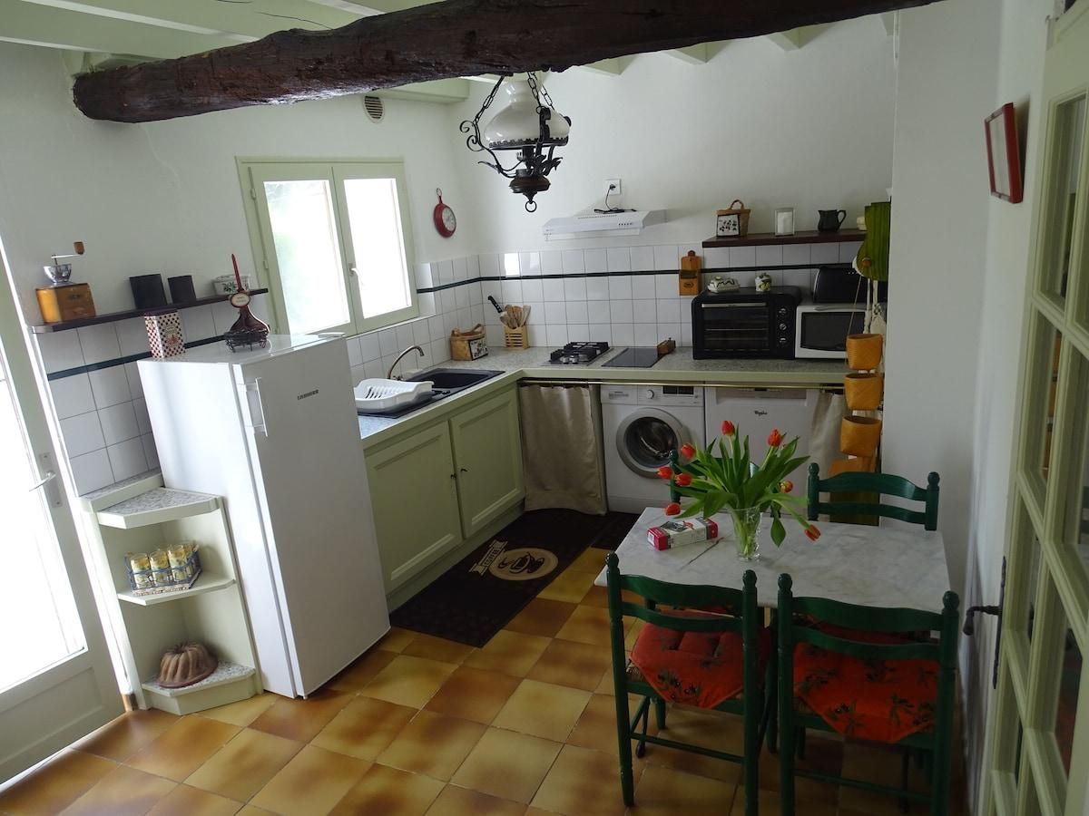 Une cuisine compacte équipée d’un lave-linge, d’une table à manger avec des chaises et d’une fenêtre.