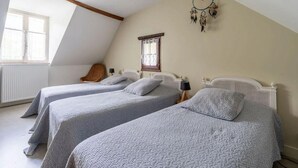 A bedroom with two beds, a sloped ceiling, a window, and a dreamcatcher on the wall.