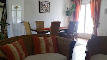 Een zithoek met een bank, stoelen, een eettafel en een glazen salontafel.