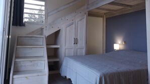 Een slaapkamer met een stapelbed, een klein bureau en een raam met gordijnen.