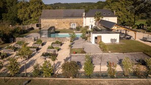 Una casa grande con piscina, terraza cubierta y jardín.
