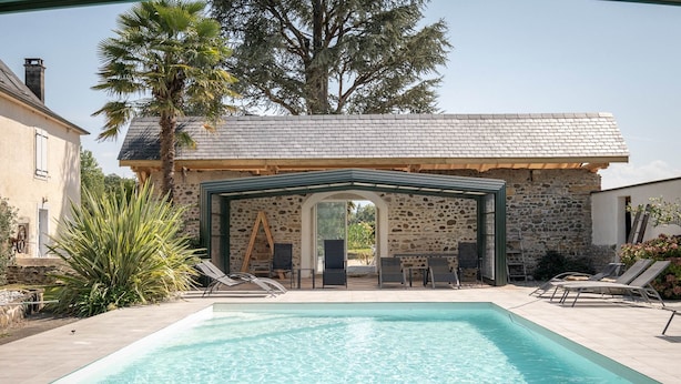 Una piscina con lettini e una zona relax coperta.