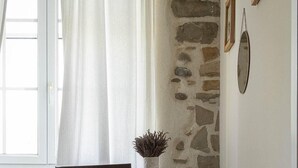 Un comedor con pared de piedra, una silla de madera, una mesa y una cesta de mimbre.