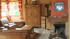 A cozy living room with a sofa, wooden cabinet, fireplace, and a window with curtains. - GUEST ROOM 2 PEOPLE IN PRETTY SAVOYARD HOUSE (Mercury)