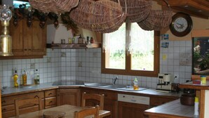 A kitchen with wooden cabinets, a dining table, and a window with a view of greenery. - GUEST ROOM 2 PEOPLE IN PRETTY SAVOYARD HOUSE (Mercury)