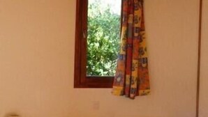 A room with a bed, a window with curtains, and a wooden ceiling.