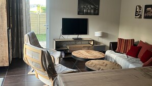 Una sala de estar moderna con un sofá, un sillón, una mesa de centro, un televisor y un cuadro en la pared.