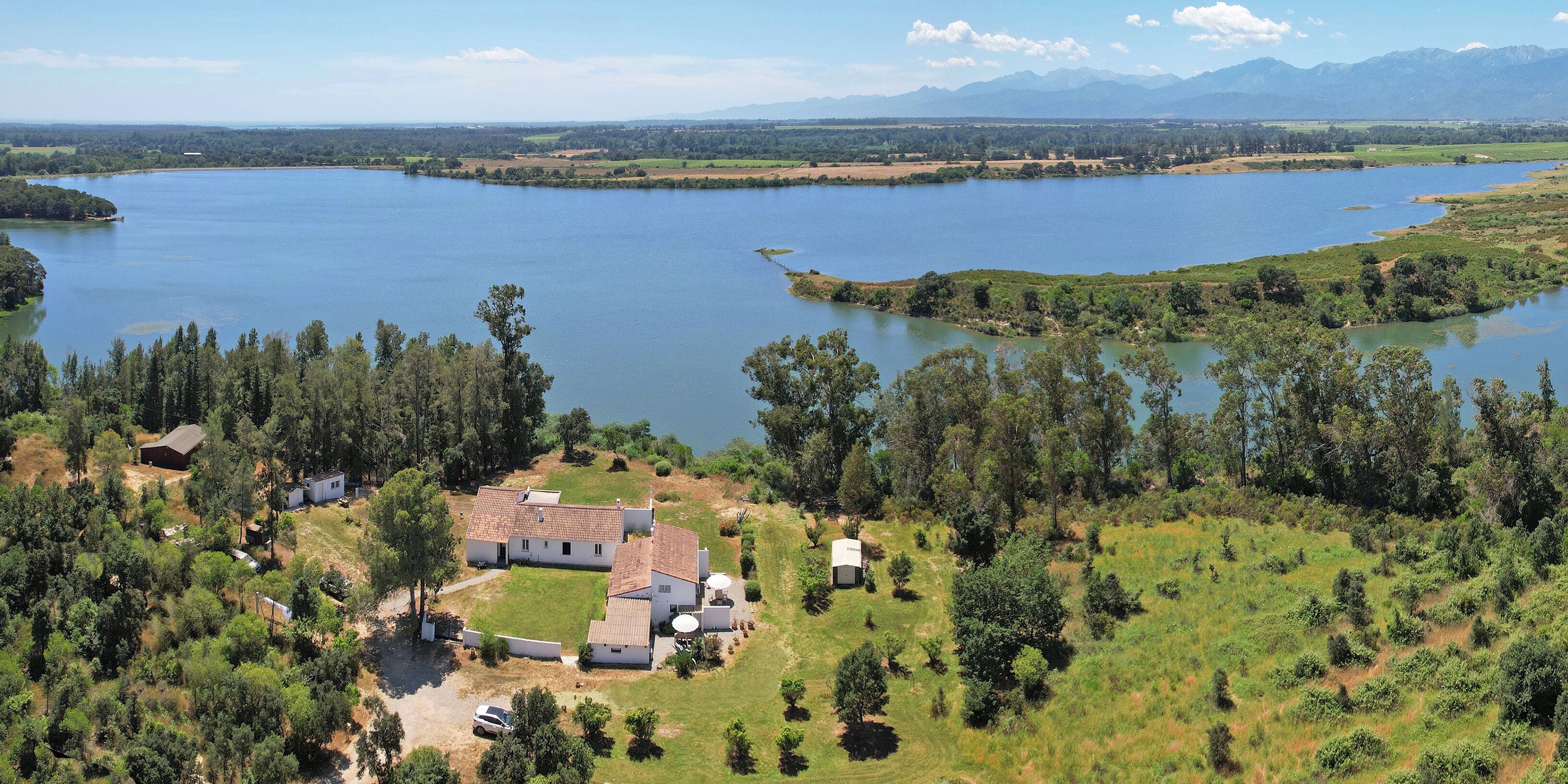 Una propiedad junto al lago con una casa, un garaje y un cobertizo pequeño.