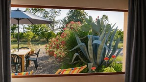 Vista a través de una ventana de un comedor con una mesa, sillas y una planta en maceta.