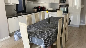 Una cocina moderna con armarios blancos, encimera negra y una mesa de comedor con mantel estampado de lunares.