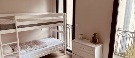 A bunk bed with a dresser and a window.