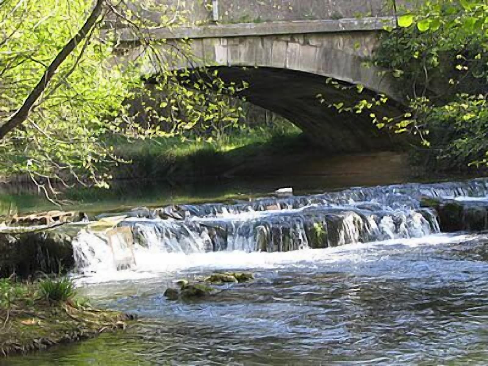 A stone bridge over a river with a small waterfall.