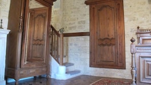 A room with a stone wall, wooden cabinets, a staircase, and a patterned rug. - Château d'Asnieres en Bessin (Asnieres-en-Bessin)