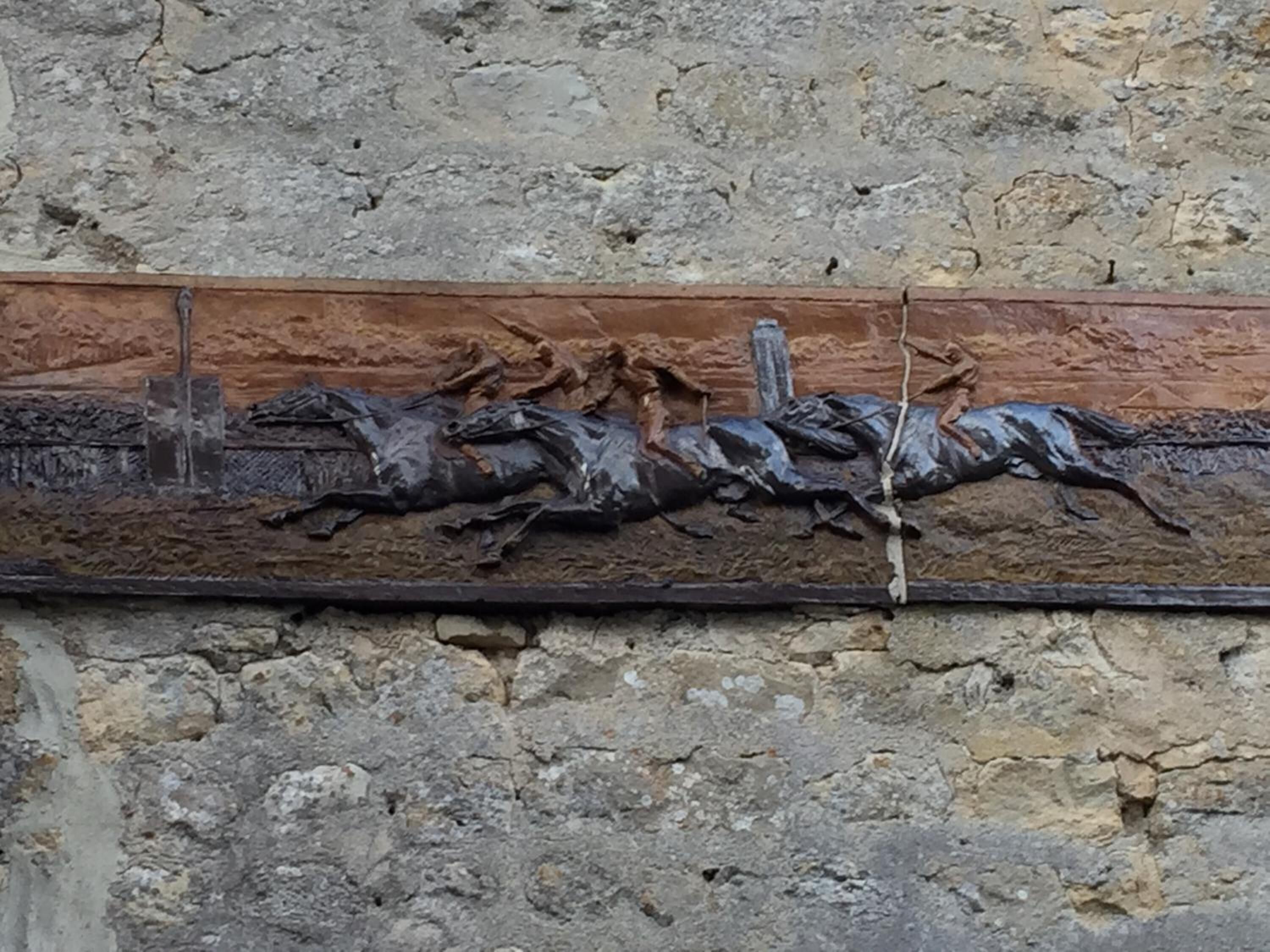 Un baix relleu detallat amb figures de cavalls tallades en pedra.