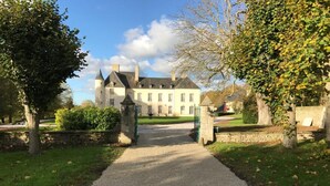 A gravel driveway leading to a large, light-colored building with multiple chimneys and windows. - Château d'Asnieres en Bessin (Asnieres-en-Bessin)