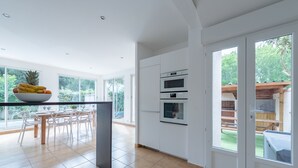 A modern kitchen with white cabinets, a built-in oven, and a large window overlooking a garden. - Villa Olivier with a private pool—10 minutes from the beach (Bompas)