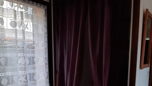 Une chambre dotée d’une porte coulissante, d’un petit réfrigérateur et d’un rideau à motifs.