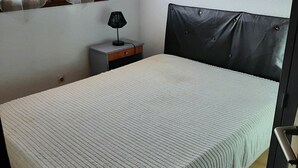 Une chambre à coucher avec un lit, une table de chevet, une lampe et une fenêtre avec des rideaux.