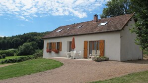 A house with a tiled roof, a gravel driveway, and a garden with a path leading to the entrance.