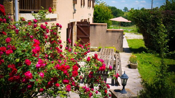 A building with a stone facade, wooden balcony, and a garden with red roses. -  ... Charming Residence in the heart of Gascony, with Jacuzzi & sauna (Estipouy)